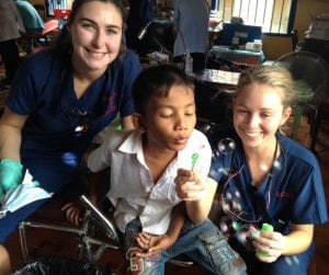 CSU students with a Cambodian child blowing bubbles