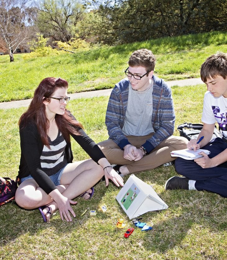 Students sitting on the grass in a circle talking