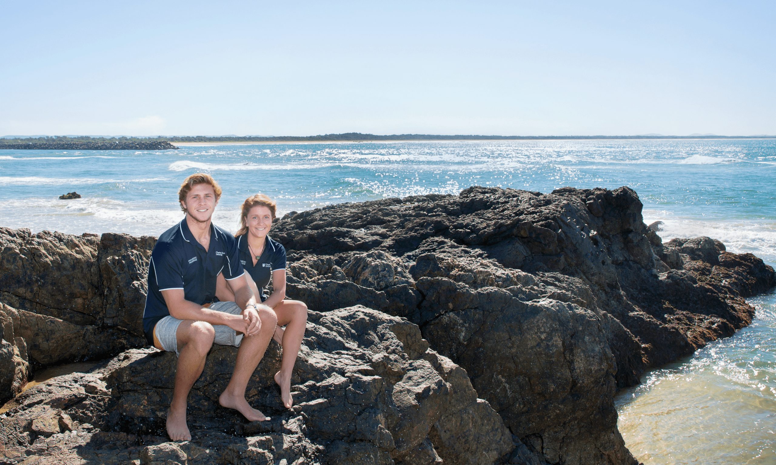 Two Port Mac students sitting on rocks at the Port Mac beach