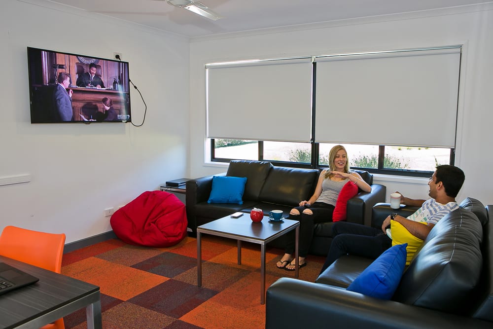 Two students watching TV in accommodation common area