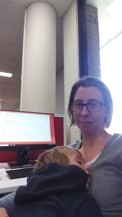 Katherine holding one of her bubs while studying.