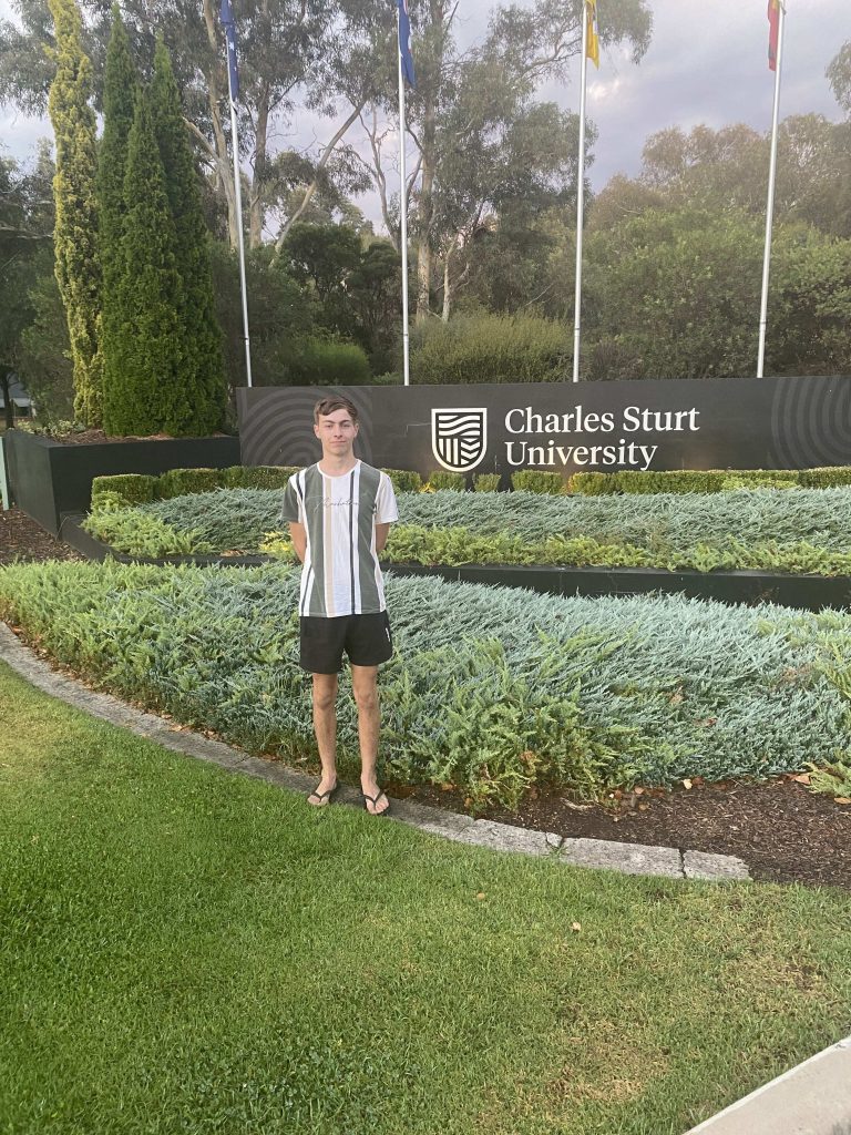 Cooper and his first year photo with the Charles Sturt sign.