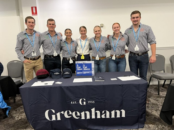 Seven students standing linked together behind a table.