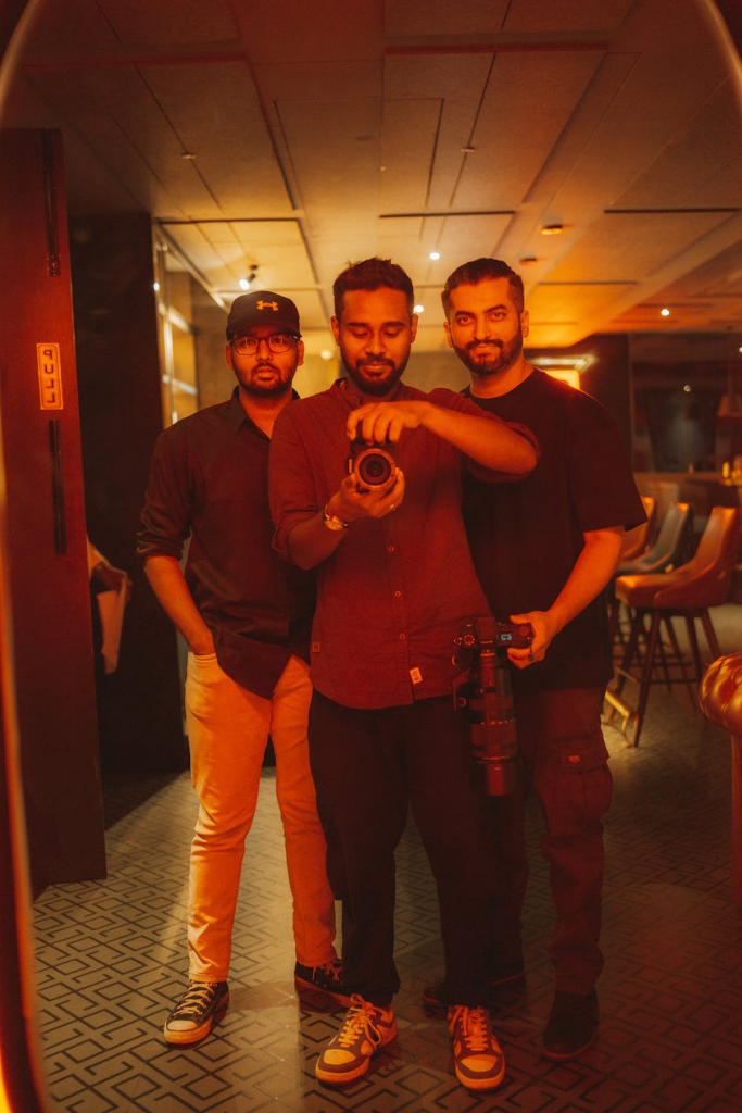 Three men looking at a camera through a mirror.