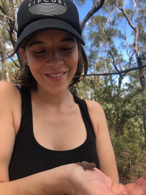 A young woman holding a gecko in the palm of her hand.